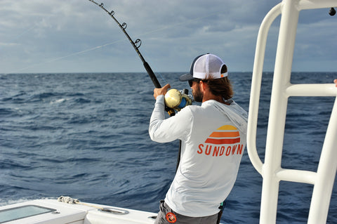 Man fishing on boat wearing Sundown Bamboo Sun shirt with large Sundown Logo on back