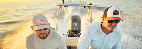 Two men on boat wearing Sundown Supply Co hats