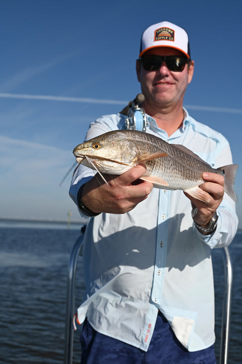 man holding fish wearing Orange/Navy/White Sundown Supply Meshback Snapback