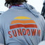 Back view of a person wearing a hoodie with 'Sundown' logo on the back
