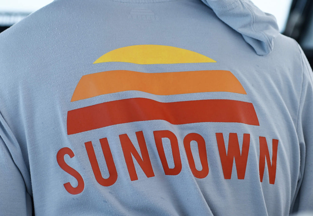 Back view of a person wearing a hoodie with 'Sundown' logo on the back