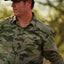 Man wearing a camouflage shirt outdoors with a blurred natural background