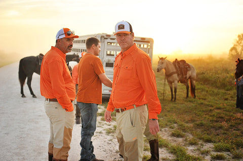 Man on ranch wearing Orange/Navy/White Sundown Supply Meshback Snapback