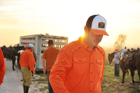 Man on ranch wearing Orange/Navy/White Sundown Supply Meshback Snapback