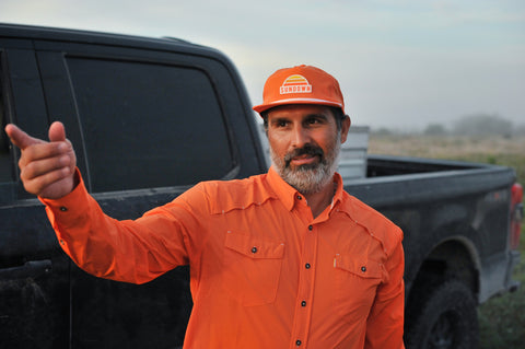 Man wearing rear view of Blaze Unstructured 5-Panel Rope Cap and l/s blaze field shirt in front of truck