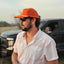 side view of man standing in front of truck wearing white performance field shirt short sleeve and blaze sundown hat