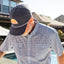 Man wearing a checkered shirt and a cap with a logo outdoors