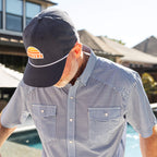 Man wearing a checkered shirt and a cap with a logo outdoors