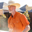 Man wearing an orange shirt and straw hat outdoors