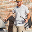 Man using a grill outdoors with a brick wall background