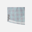 Closeup of bottom side edge of Seafoam/Grey Plaid Pearl Snap Field Shirt S/S showing grey side slits with black "SUNDOWN" text